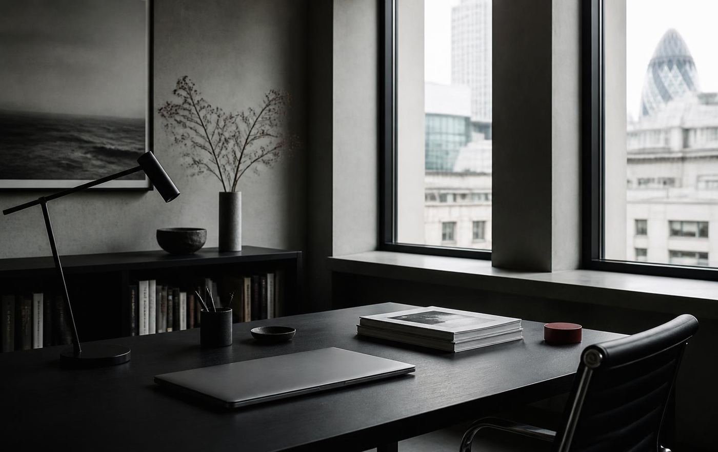 A quiet London workspace with a desk, closed laptop and neatly stacked documents